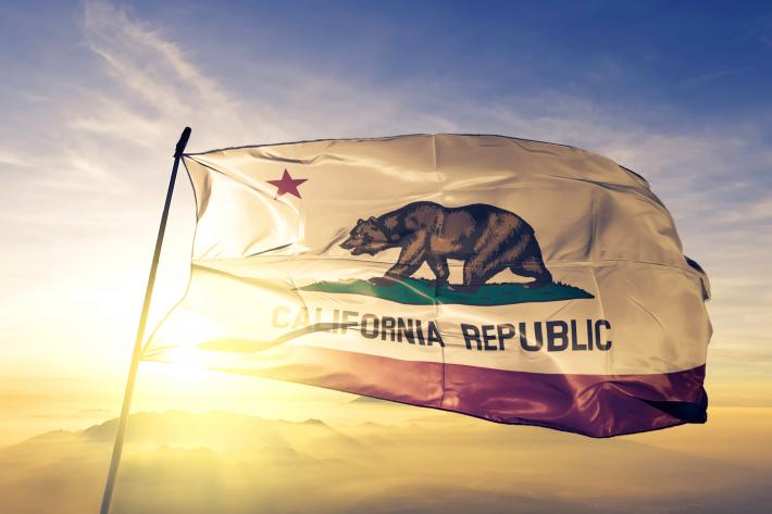 A California state flag waves in a strong wind.