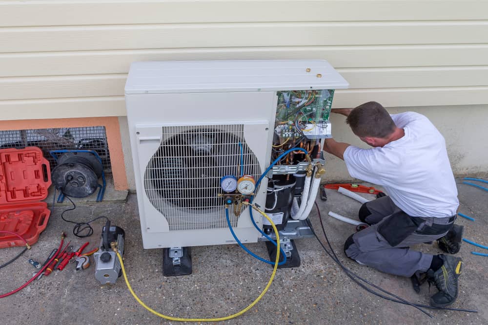 Technician checking pressure of refrigerant of heat pump to make sure it is operating at more than 100% efficiency.
