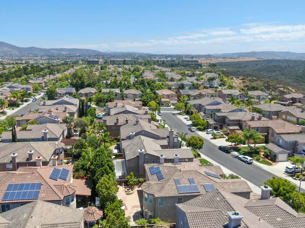 View of San Diego horizon foregrounded by hundreds of roofs with solar panel installations.